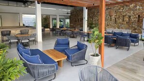 An indoor patio area with seating arrangements and a stone wall backdrop. - Baia Kristal Experience Apartment (Cartagena)