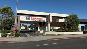 A motel with a large sign, a covered parking area, and a clear blue sky.