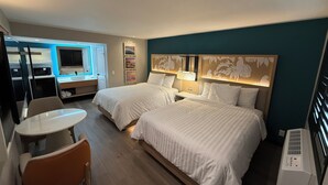 A hotel room with two beds, a desk, a chair, a bathroom, and a TV.