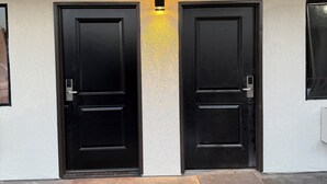 A building with two black doors, a textured wall, and a small illuminated panel above the doors.