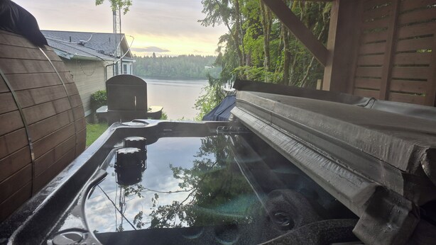 Een hottub met uitzicht op een meer en bomen.