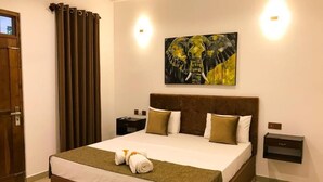 Una habitación de hotel con una cama grande, cabecera, dos mesitas de noche, un cuadro en la pared y una puerta con cortinas.