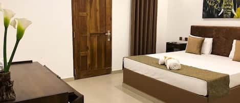 Un dormitorio con puerta de madera, cama con cabecero marrón, mesita de noche y un cuadro de un elefante.