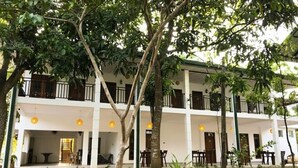 Un edificio de varios pisos con balcones, mobiliario exterior y un césped cuidado.