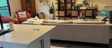 A modern kitchen with a central island, wooden flooring, and pendant lighting.