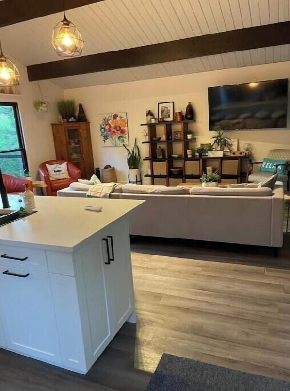 Una cocina moderna con isla central, piso de madera e iluminación colgante.