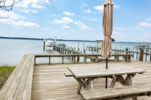 A wooden dock with a picnic table and umbrella, overlooking a calm lake with docks in the distance. - Dock, Boat Lift & Golf Cart on Alligator Point (Alligator Point)