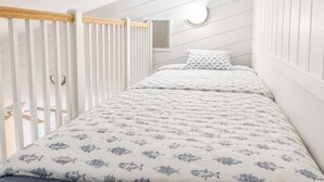 Quarto com beliche, paredes brancas, corrimão de madeira e luminária circular.