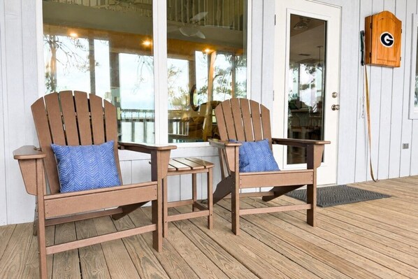 Two wooden Adirondack chairs with blue cushions on a wooden deck, a door with a mailbox, and a view of the outdoors. - Dock, Boat Lift & Golf Cart on Alligator Point (Alligator Point)