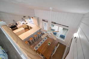 Eine moderne Küche mit einer zentralen Kochinsel, Essbereich mit Holztisch und Stühlen sowie Deckenventilator.