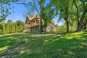 Un grand bâtiment en bois doté de nombreux balcons, entouré d’arbres verdoyants et d’une pelouse bien entretenue.