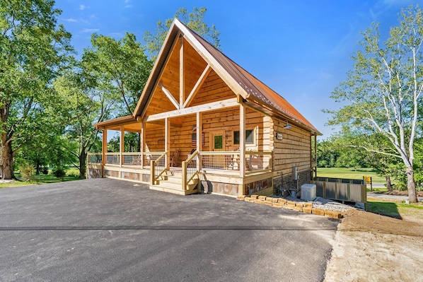 Une cabane en bois dotée d’un porche, d’une entrée couverte et d’une allée pavée.