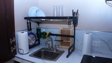 Una cocina con un lavamanos, un escurreplatos y una tabla de cortar de madera.
