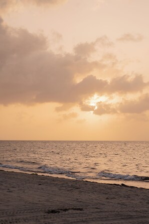 A beach with waves and a cloudy sky.