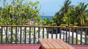 A balcony with a wooden bench, a railing, and a view of the ocean and palm trees. - HOTEL LOS AMIGOS  (Puerto Cortés)