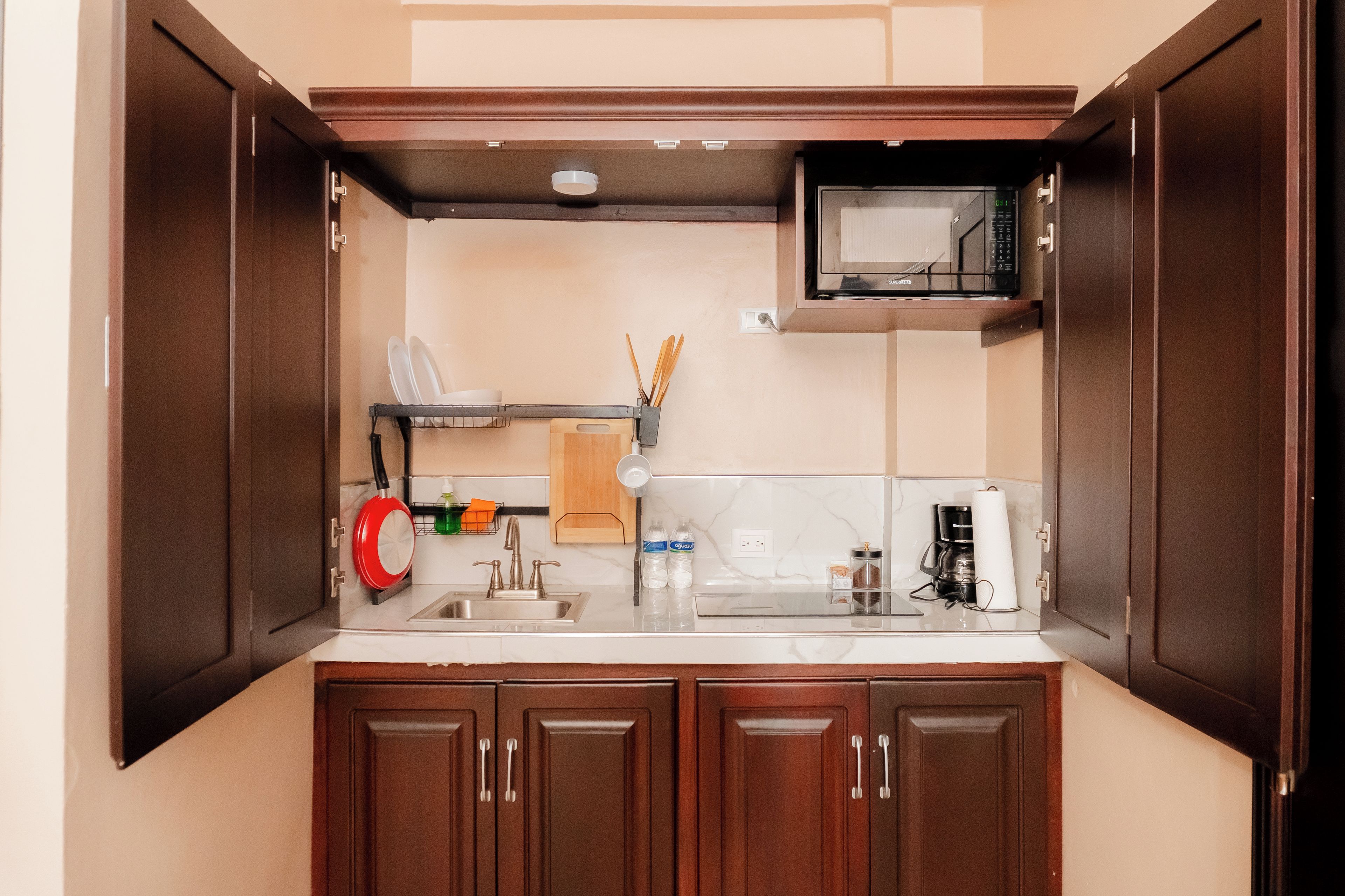 A compact kitchen with a microwave, sink, and cabinets.