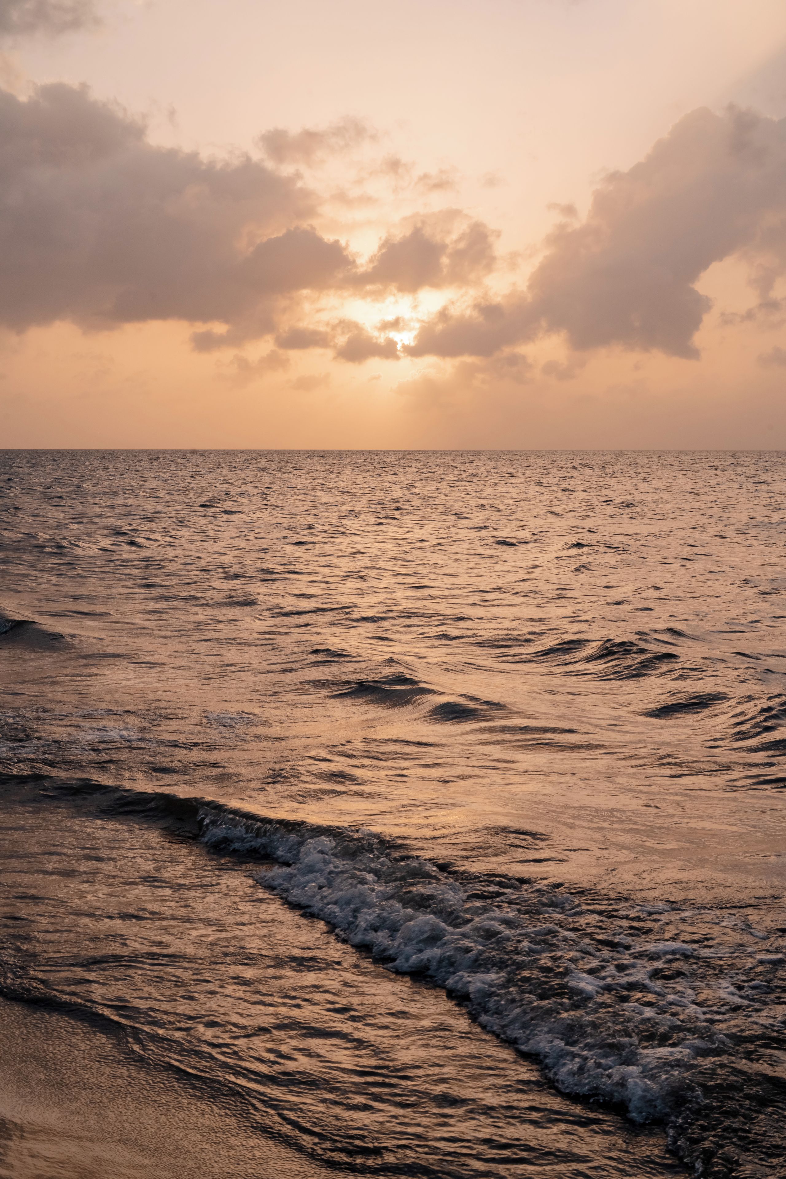 A beach with waves and a sunset.