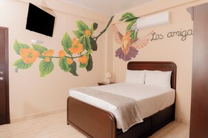 Un dormitorio con una cama, aire acondicionado de pared y un mural de flores y un pájaro.