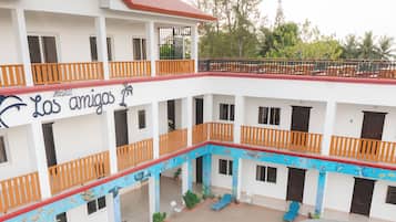 A hotel with multiple balconies, a swimming pool, and a covered outdoor area.