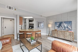 A modern living room with a kitchen area, leather sofas, a coffee table, a TV, and a patterned cabinet. - Location! Luxury Main St Condo - Walk to Town Lift (Park City)