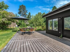 A wooden deck with a table and chairs, surrounded by lush greenery and trees. - "Franki" - 1.8km from the sea by Interhome (Faxe)