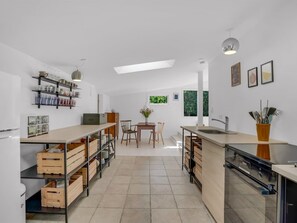 A modern kitchen with a central island, wooden storage, and a dining area with natural light. - "Franki" - 1.8km from the sea by Interhome (Faxe)