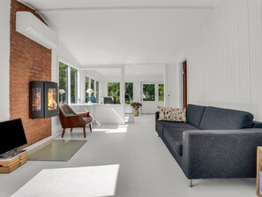 Un salon moderne doté d’une cheminée, d’un canapé, d’un téléviseur et d’un coin repas baigné de lumière naturelle.