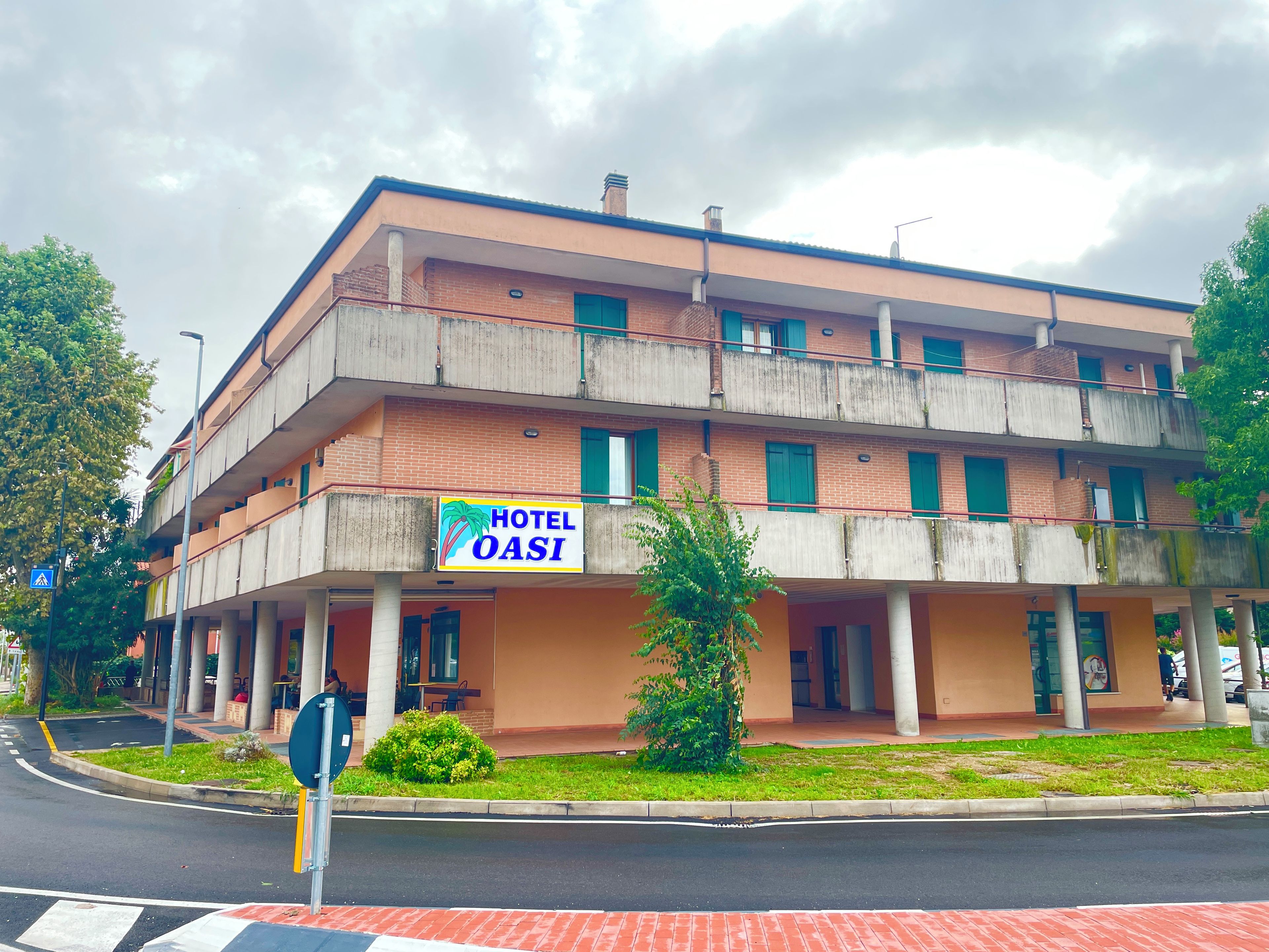Un edificio de varios pisos con un letrero que dice 'HOTEL OASI' y una entrada visible.