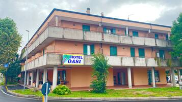 Un edificio de varios pisos con un letrero que dice 'HOTEL OASI' y una entrada visible.