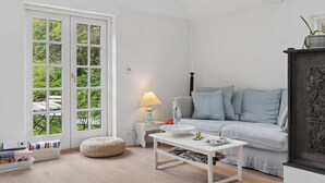 Een moderne woonkamer met een bank, een salontafel, een lamp en een boekenkast.