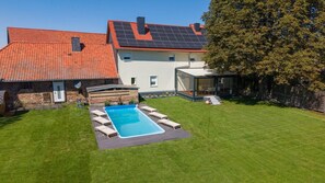 A residential property with a swimming pool, a covered outdoor seating area, and a solar panel roof.