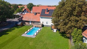 En boligejendom med swimmingpool, velplejet græsplæne og rødt tegltag.