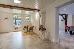 A spacious room with a wooden ceiling, a dining area with chairs and a table, and a large window with a view. - Elementa Lodges Wernigerode-Reddeber (Reddeber)