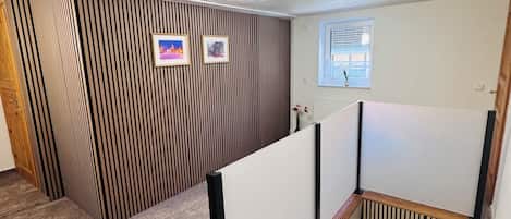 A room with a sloped ceiling, a wooden staircase, and a window with blinds.