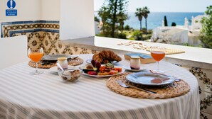 A breakfast table with various foods and drinks, a view of the sea, and a sign indicating a children's area. - New Listing | Exclusive Ocean View Villa | 2Min to Beach (Armação de Pêra)