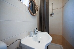 A bathroom with a white sink, a towel rack, and a shower area. - Stela Mala Apartment (Rovinj)