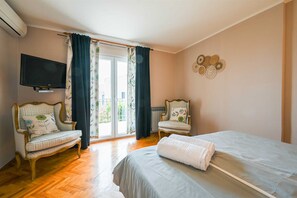 Une chambre d’hôtel avec un lit, deux fauteuils, une télévision et une vue sur l’extérieur.