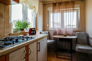 A compact kitchen with a gas stove, a small table, and a chair. - Stela Mala Apartment (Rovinj)