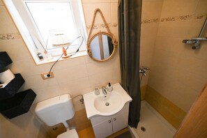 Une salle de bain équipée de toilettes, d’un lavabo, d’un miroir et d’une douche.