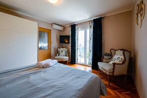 A hotel room with a bed, two chairs, a television, and a sliding glass door to the outside. - Stela Mala Apartment (Rovinj)