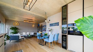 A modern kitchen with a dining area, wooden flooring, and a large green plant. - Stela Vela Apartment (Rovinj)