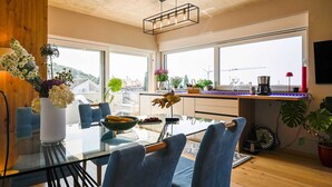 A modern kitchen with large windows, a dining area with a glass table, and various plants. - Stela Vela Apartment (Rovinj)