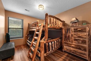 A bunk bed with a rustic wooden design, a small bench, and a dresser with a similar style.