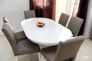 Ein Esstisch mit Obstschale, umgeben von vier Stühlen.