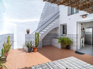 Eine moderne Außenpatio mit gefliestem Boden, Topfpflanzen, einer Treppe und einem Küchenbereich.