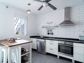 A modern kitchen with white cabinetry, a black countertop, a built-in oven, and a ceiling fan. - Casa San Juan 13 Centro by Casasol by Interhome (Nerja)