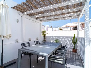 An outdoor patio with a table and chairs, a pergola, and a potted plant. - Casa San Juan 13 Centro by Casasol by Interhome (Nerja)