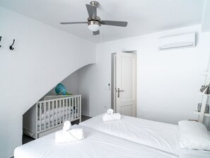 A hotel room with a bed, a crib, a ceiling fan, and a door. - Casa San Juan 13 Centro by Casasol by Interhome (Nerja)