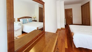 Een hotelkamer met twee bedden, een houten vloer, een grote spiegel en een houten kledingkast.
