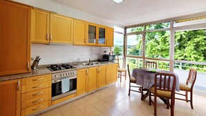 Een keuken met houten kastjes, een gasfornuis en een eethoek met een tafel en stoelen.